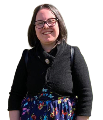 Lindsay, wearing glasses and smiling, dressed in a black cardigan over a colorful floral dress